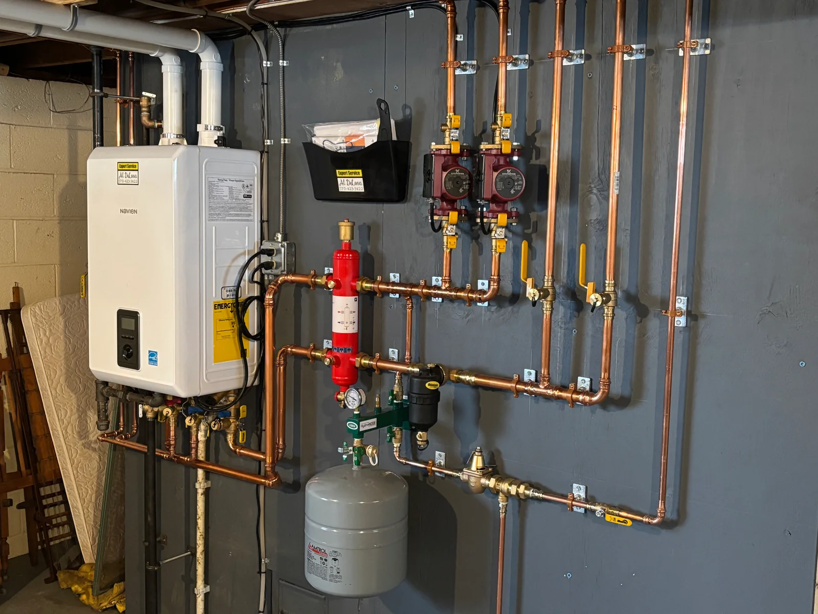 Tankless water heater with dual pump stations, copper piping, pressure relief tanks, and backflow prevention valves