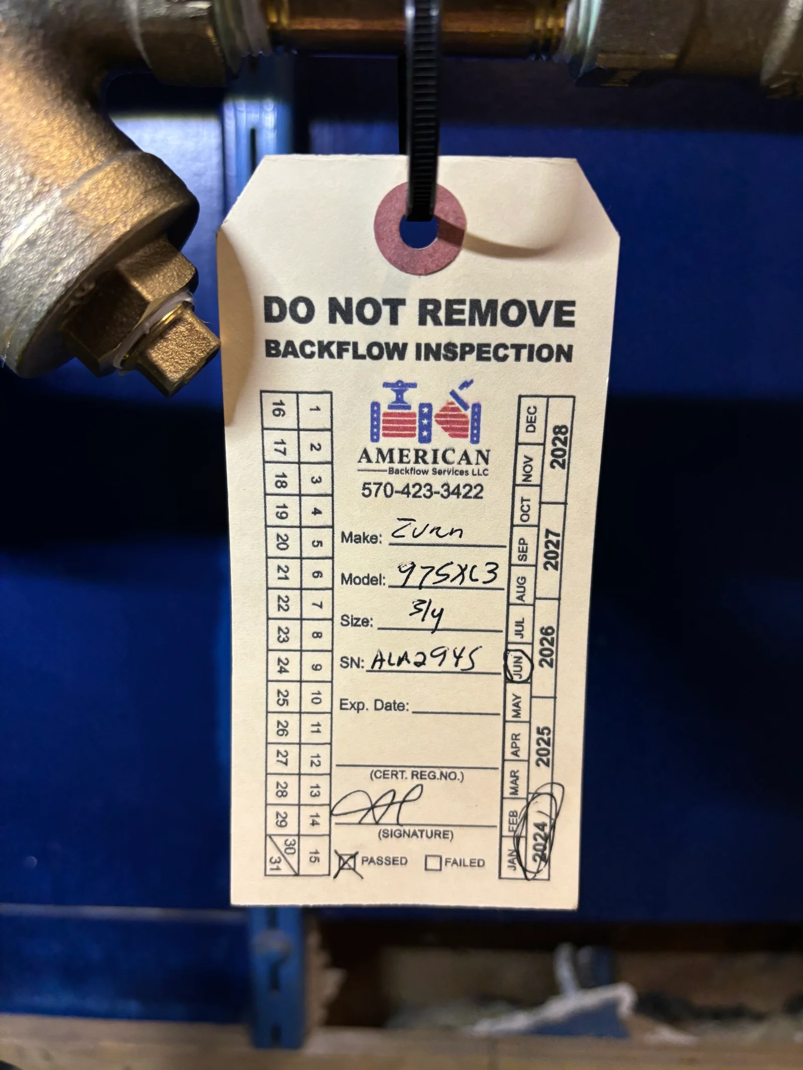 Backflow prevention device with inspection tag showing Evenflo model 975X13, size 3/4, passed certification status