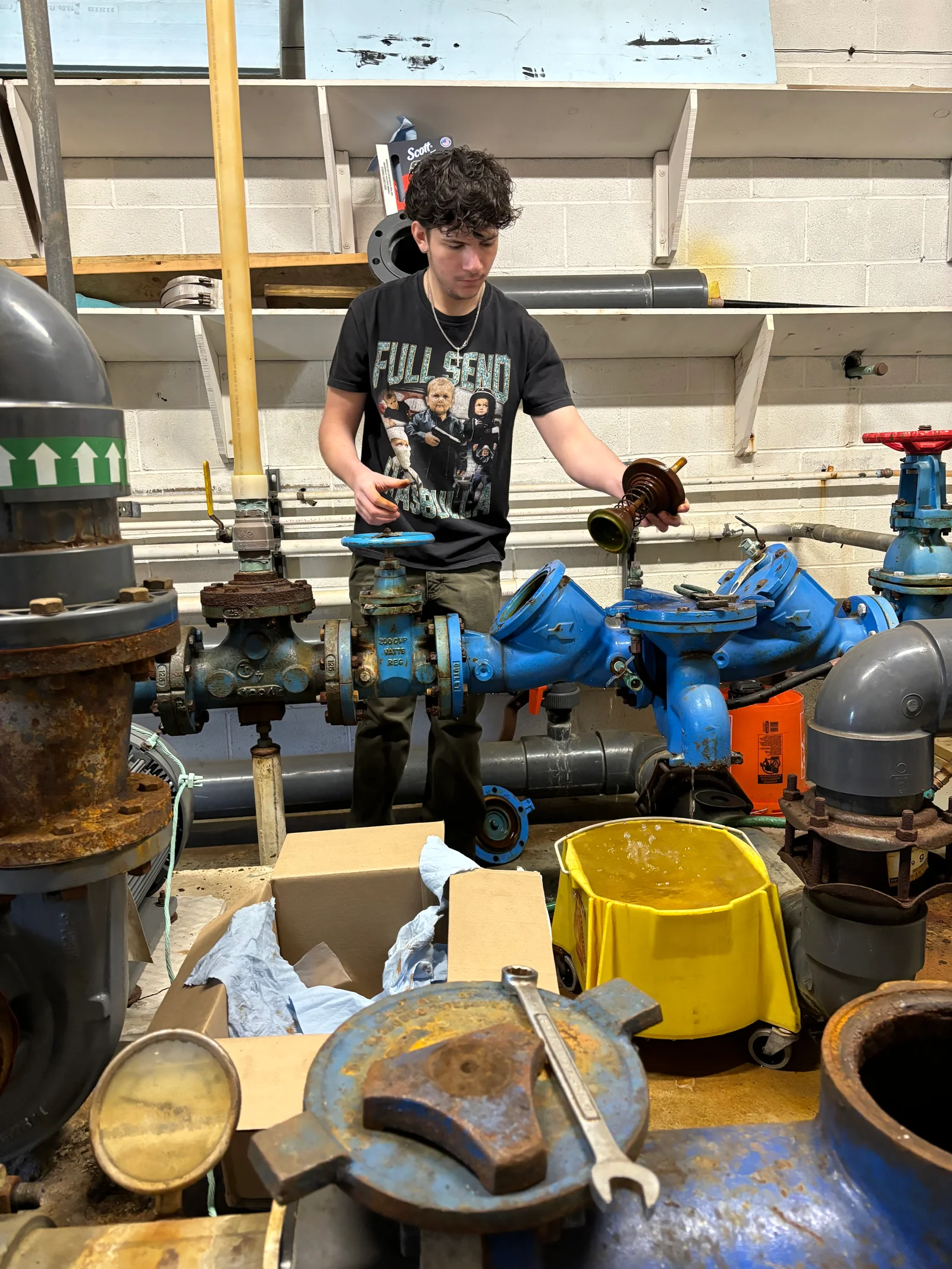 Technician assembling blue check valves and ball valves on black pipe backflow prevention manifold